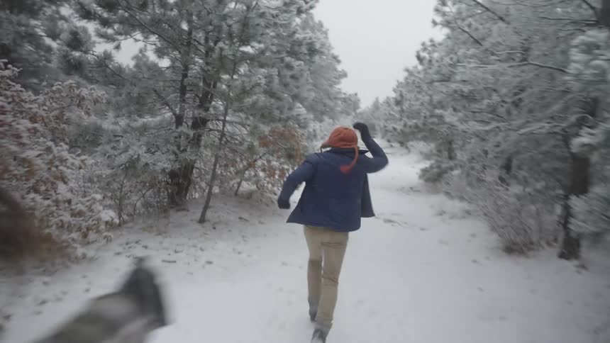The man and woman run and play in the snowy forest