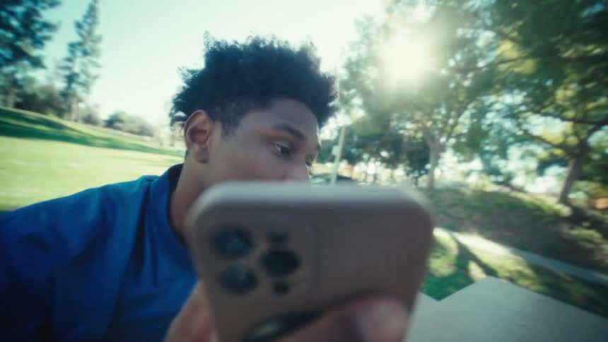 Close up of a young black male making a phone call while sitting outdoors during daytime