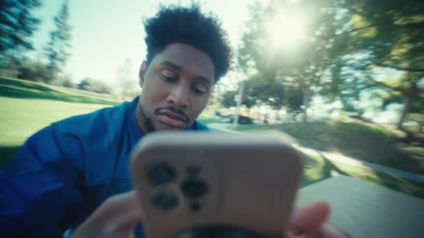 The man in the blue shirt holding the cell phone and bringing it close to his ear