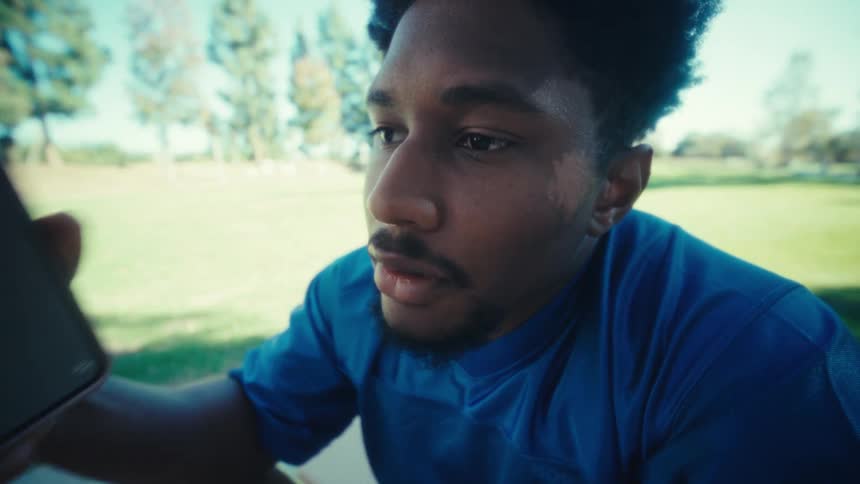 Man sitting outdoors talking on a cellphone in a park during daytime