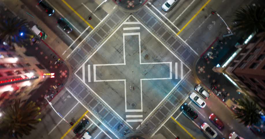 Topdown view of the intersection of Hollywood Boulevard and Vine Street with crossshaped road markings and vehicles moving along surrounding streets