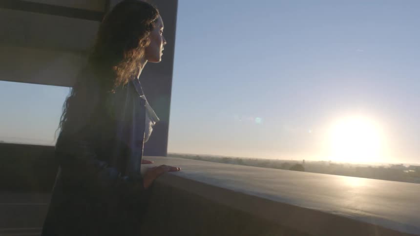 Person gazes at the horizon from a modern terrace during sunrise or sunset