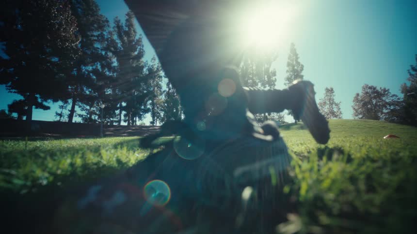 A black man practices football by running around orange cones in a sunny grassland