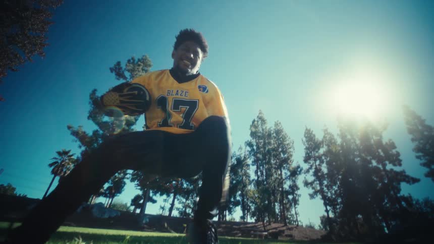 Man holding a football runs in the park on a sunny autumn day