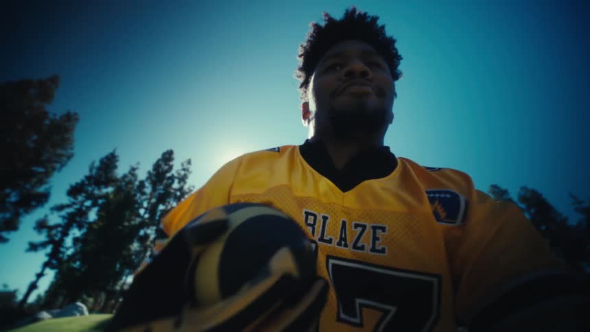 Close up of a young black male athlete recording themselves while practising american football on a field outdoors during daytime