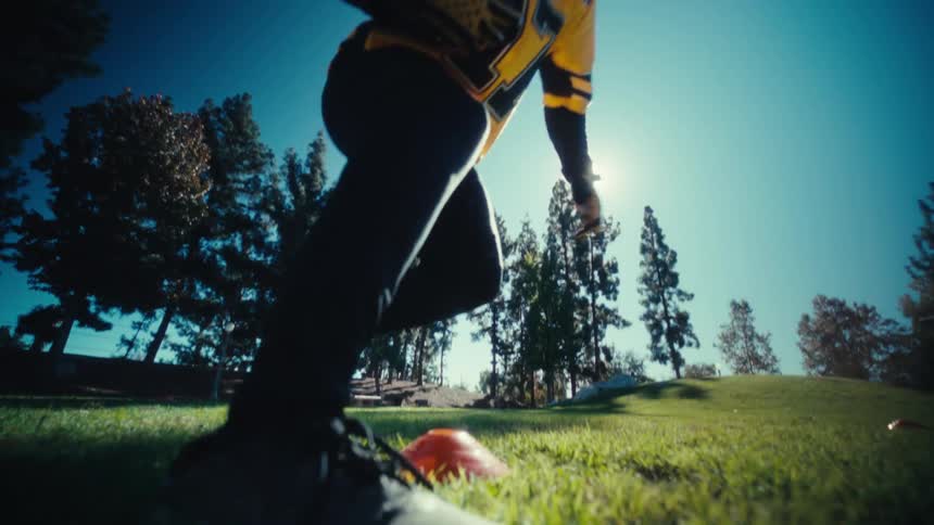 A young black male athlete practising american football on a field outdoors during daytime