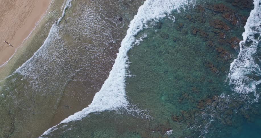 The waves move over the sand on the beach