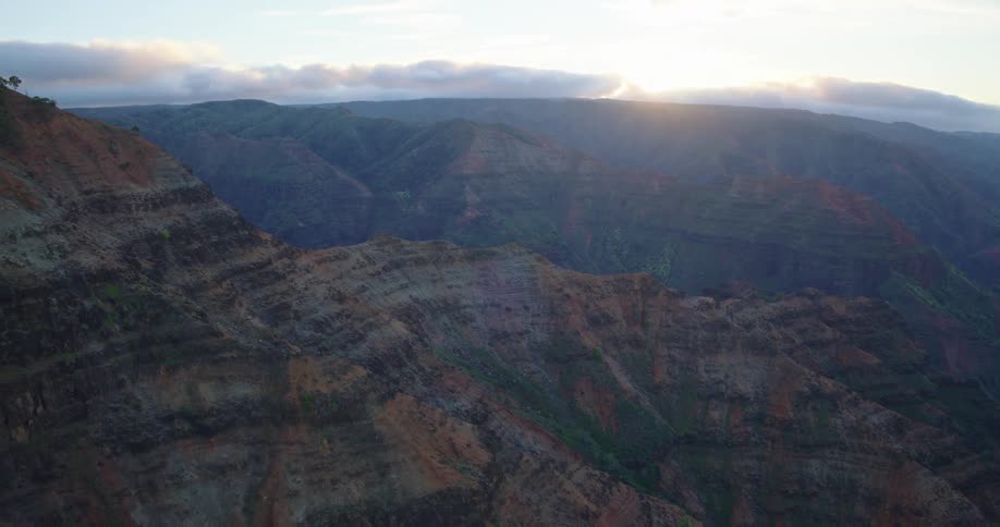 Rock formations in varied tones stretch across valleys and ridges under soft evening light