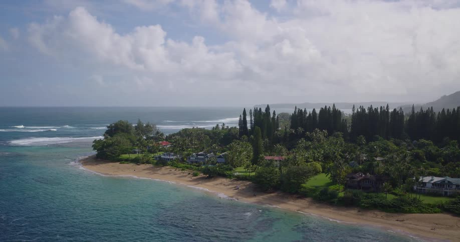 Aerial shot of a tropical beach with turquoise water green trees and waves rolling in
