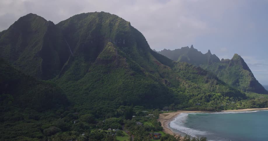 A coastal mountain is covered with a dense layer of trees and vegetation