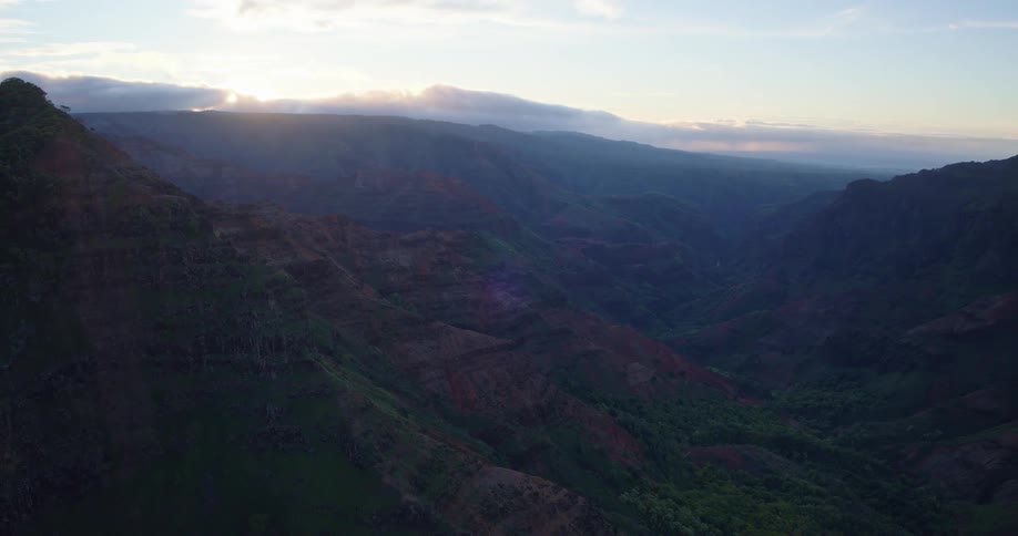 Wide canyon with rocky slopes and vegetation seen under early morning light