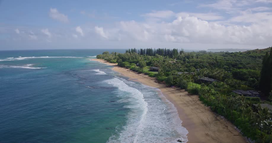 Ocean waves wash upon a sandy beach near a residential neighborhood