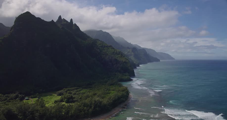 Mountainous coastline with vegetated cliffs and ocean waves along the shoreline