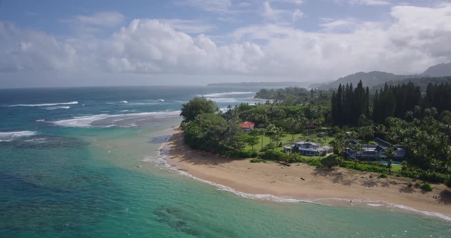 Coastline at midday with a resort nestled among trees overlooking a wide open ocean view in the background