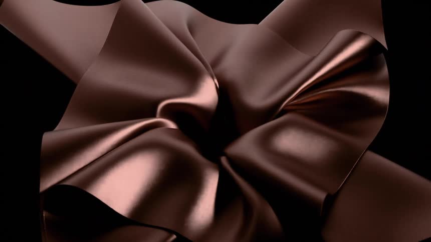 Metallic cloth collapses at the center falling against a black background