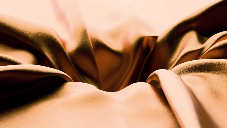 Deep folds highlight shiny peach fabric texture with soft reflections