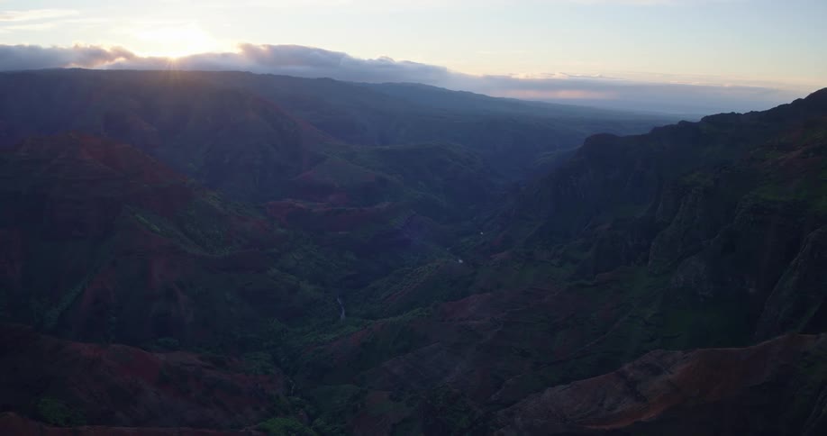 Aerial view of a vast mountain valley with layered ridges and soft sunlight at dawn