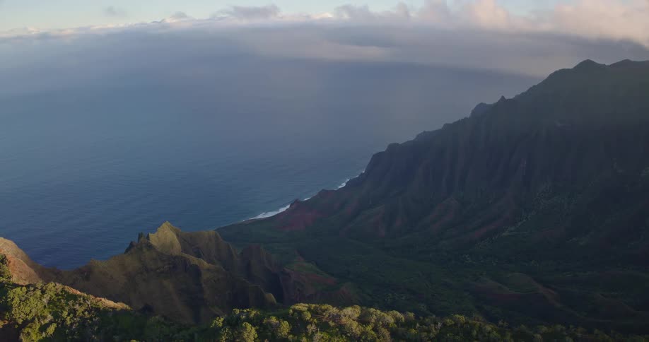 Light fog covers the mountainous coast on a cloudy summer day