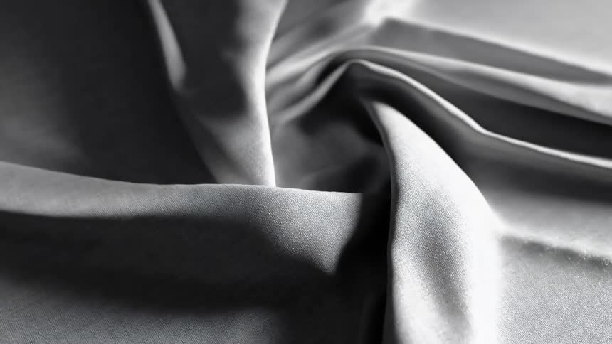 Smooth reflective gray fabric forms artistic folds with subtle shadows and highlights