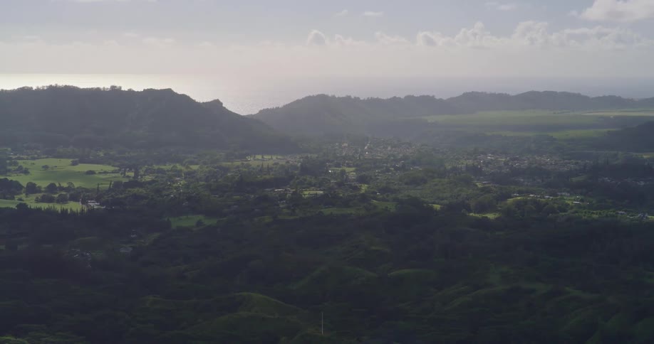 Natural landscape with flat lands and fields around a village with a mountain range in the background outdoors during day time
