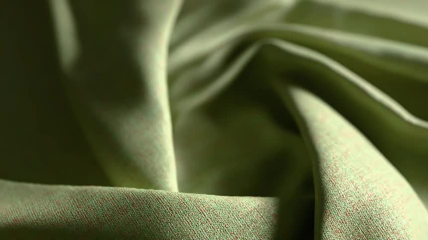 Light green fine textured fabric develops folds as it rotates forming a twisted shape