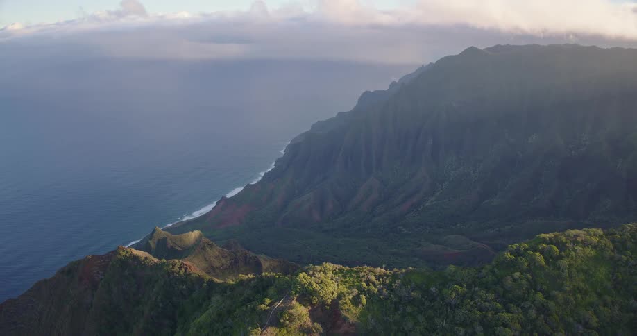 Forested mountain along the coast as waves roll in to shore