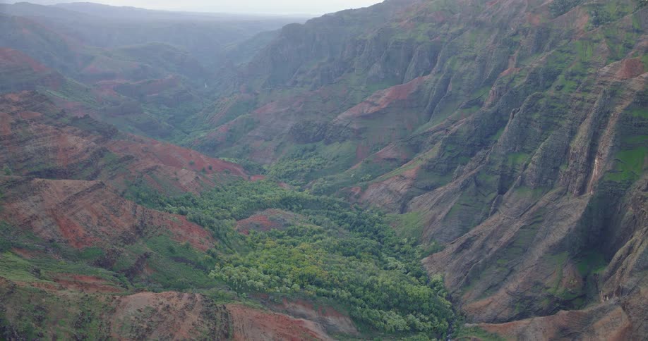 Aerial view of a deep green valley winding through steep rugged mountains
