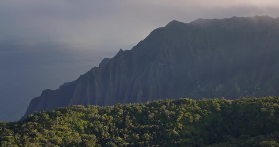 Forested mountains along the coast under a cloudy sky