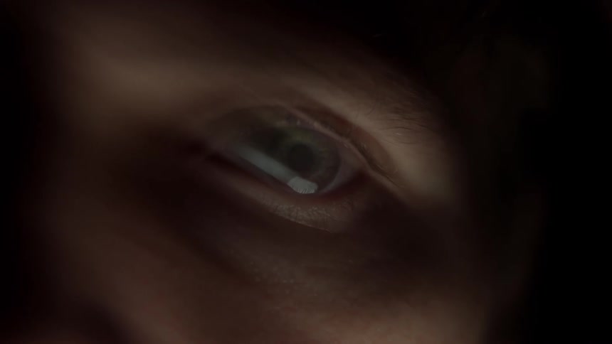 Closeup of a human eye partially illuminated with shadows covering the rest of the face