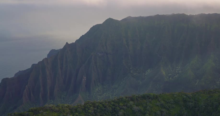 Mountain range rising from an island surrounded by lush green vegetation and natural terrain