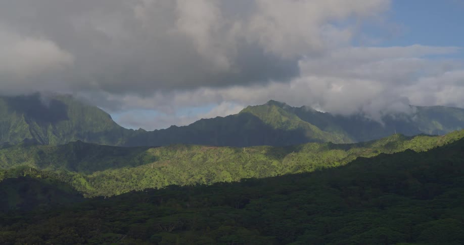Mountains covered in dense vegetation under a partly cloudy sky