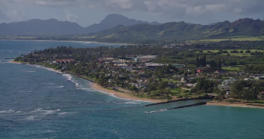 Beach with breakwater in coastal town surrounded by mountains