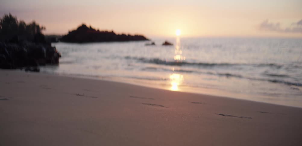 The tide is hitting the sand at sunrise