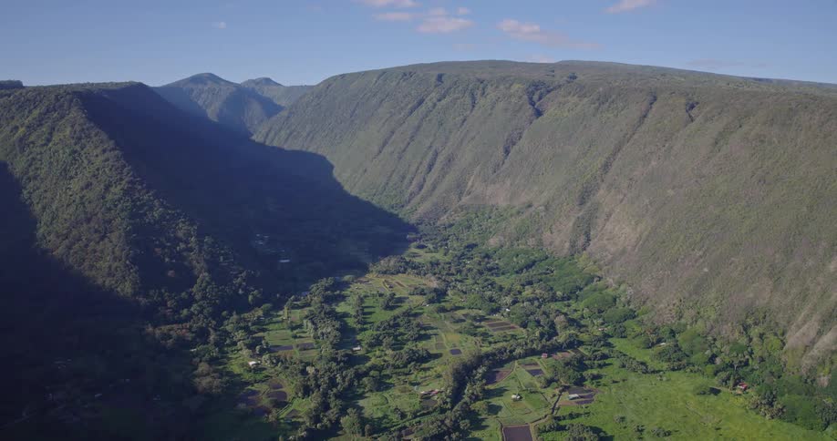 Low open landscape covered in green vegetation surrounded by mountains under bright sunny skies