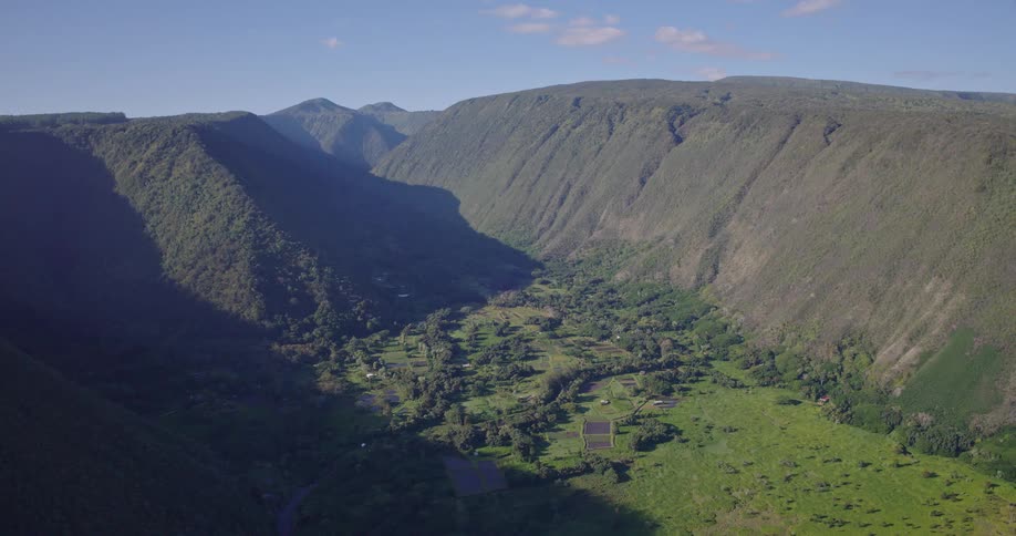 Mountain range covered in lush green vegetation under bright sunny skies