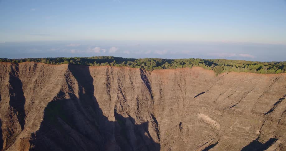Mountain range with its peaks covered in green vegetation surrounded by rugged terrain under bright sunny skies