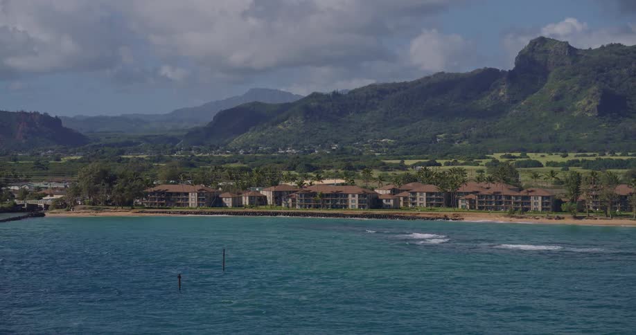 Resort along the coastline with a series of buildings facing the water backed by a mountain range in the distance