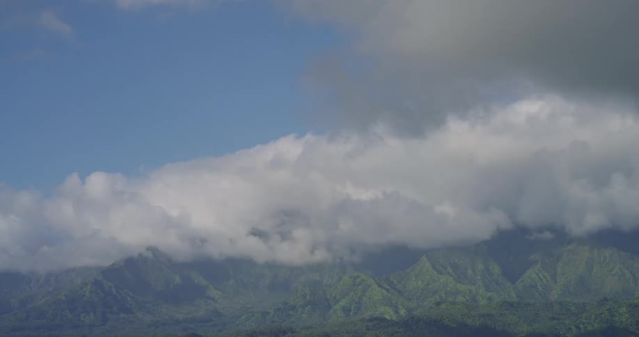 Mountainous landscape at midday with white clouds stretching across the sky above the rugged terrain