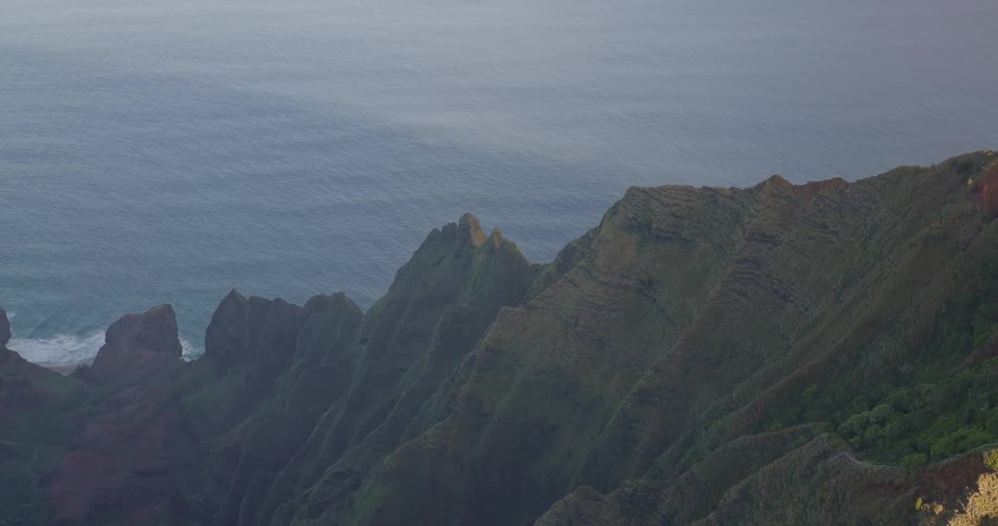 Rugged cliffs meet a calm ocean under a soft hazy sky