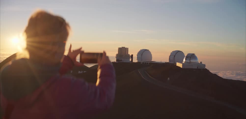 A woman using a phone to take photos of an observatory