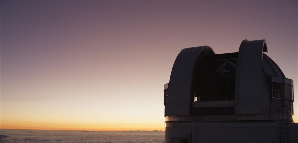 Observatory dome silhouettes against vibrant evening sky revealing telescope above the clouds