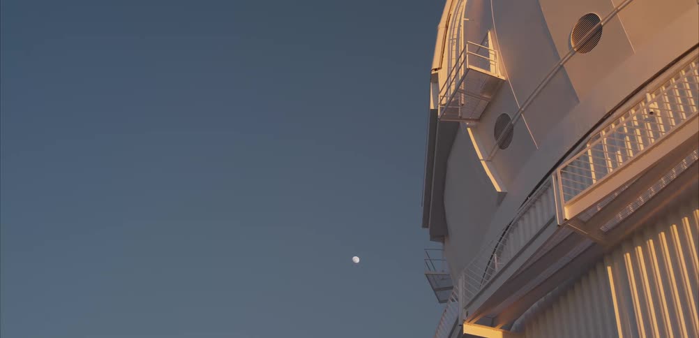 A view of an observatory with the moon in the background