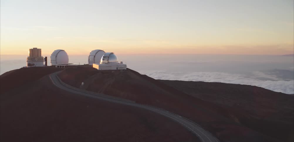 Astronomical observatories line a winding road on high mountain bathed in sunset light