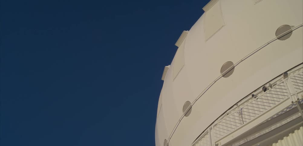 Astronomical observatory dome stands out against a blue sky when viewed from below