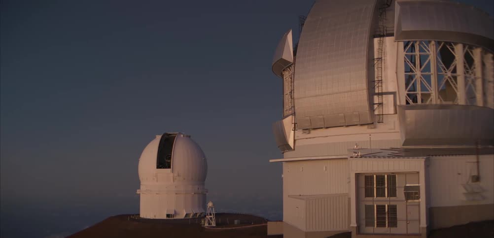 Astronomical observatories on a mountain summit with metal domes illuminated by dusk light