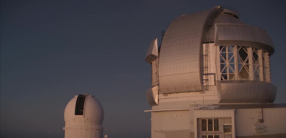 A large astronomical observatory dome stands against a clear sky during warm dusk light
