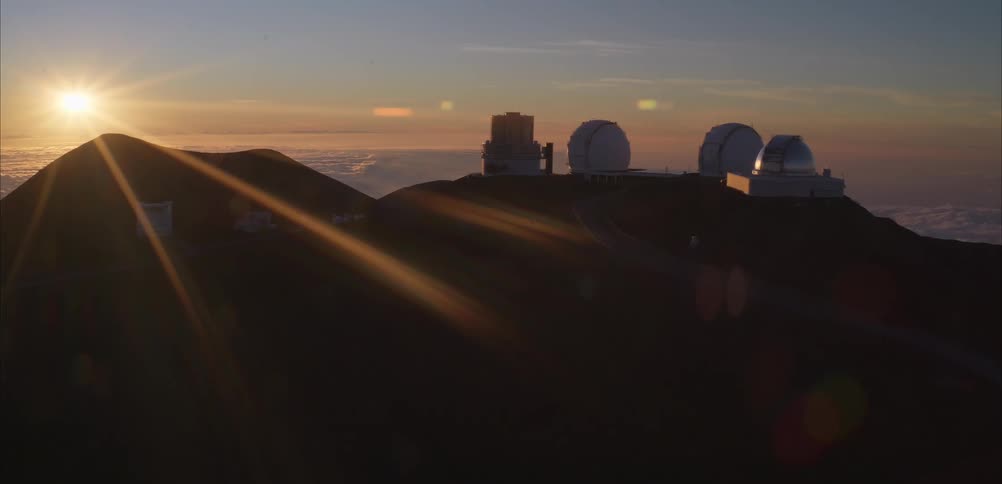 Sun shines from a red sky onto an observatory located on a hill on a foggy day