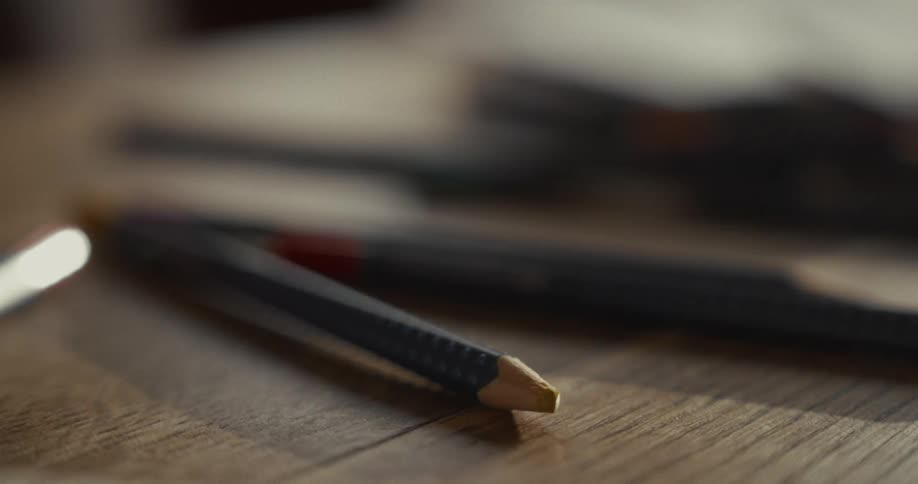 The primary line is created by a dark textured pencil lying diagonally across the foreground it starts from the lower left and extends toward the center featuring a sharp yellow lead tip that serves as a focal point