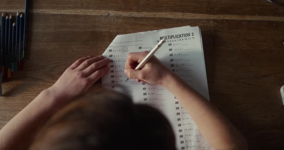 In the video a child is working on a multiplication worksheet at a wooden desk here are two lines of text visible on the page being filled outmultiplication 2 this is the main title at the top of the worksheet printed in a large clean font