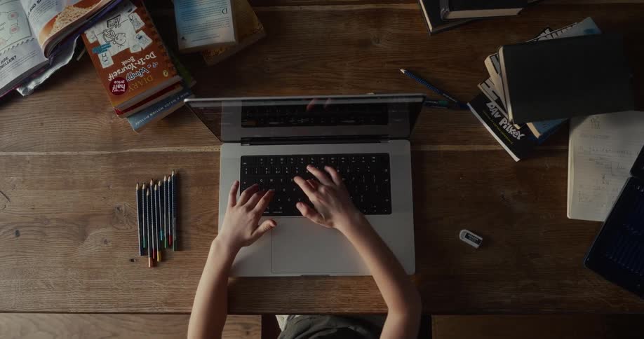 A child typing on a laptop keyboard